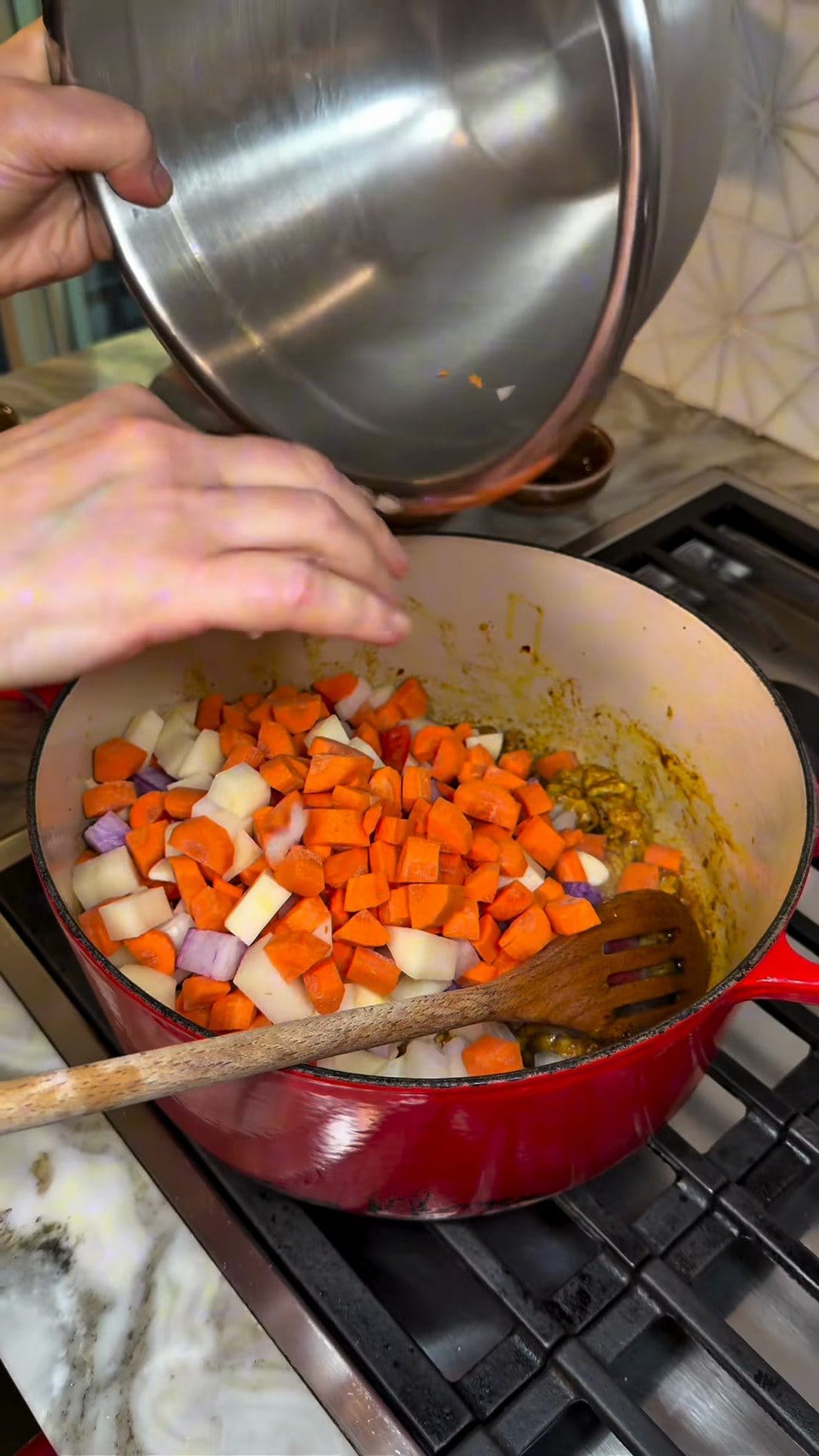 Diced carrots, radish and onion tipped from a steel bowl into the pot over the browned chicken