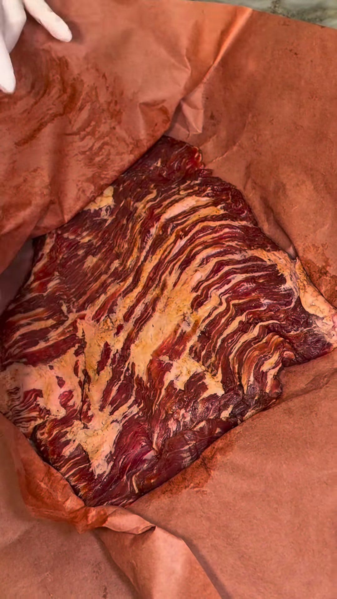 A raw, well-marbled flat cut of brisket unwrapped on pink butcher paper