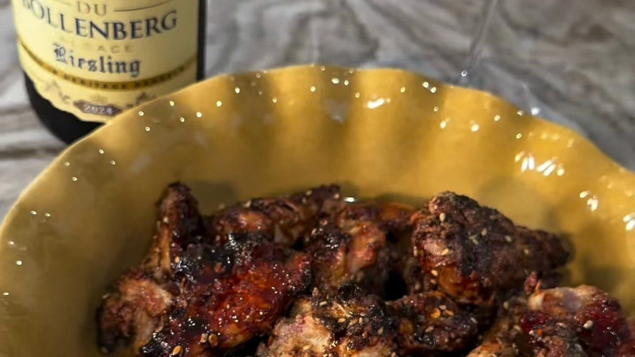 Sticky tamarind-glazed wings flecked with za'atar in a yellow bowl, the Cave du Bollenberg Riesling bottle behind