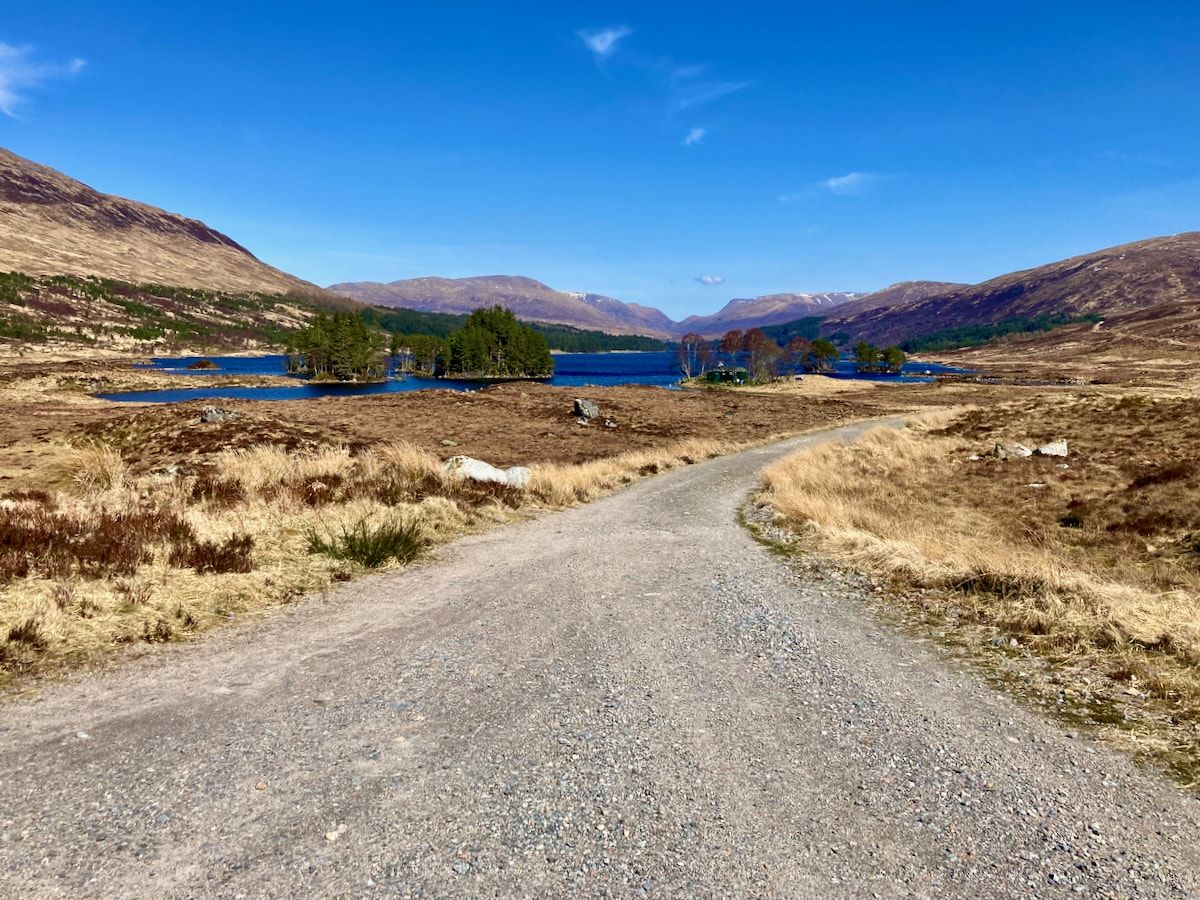 Ein Schotterweg, im Hintergrund der See