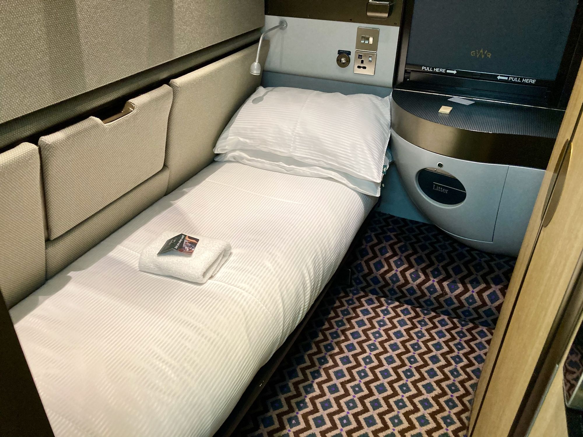 Einzelabteil mit Bett, Handtüchern und Waschbecken