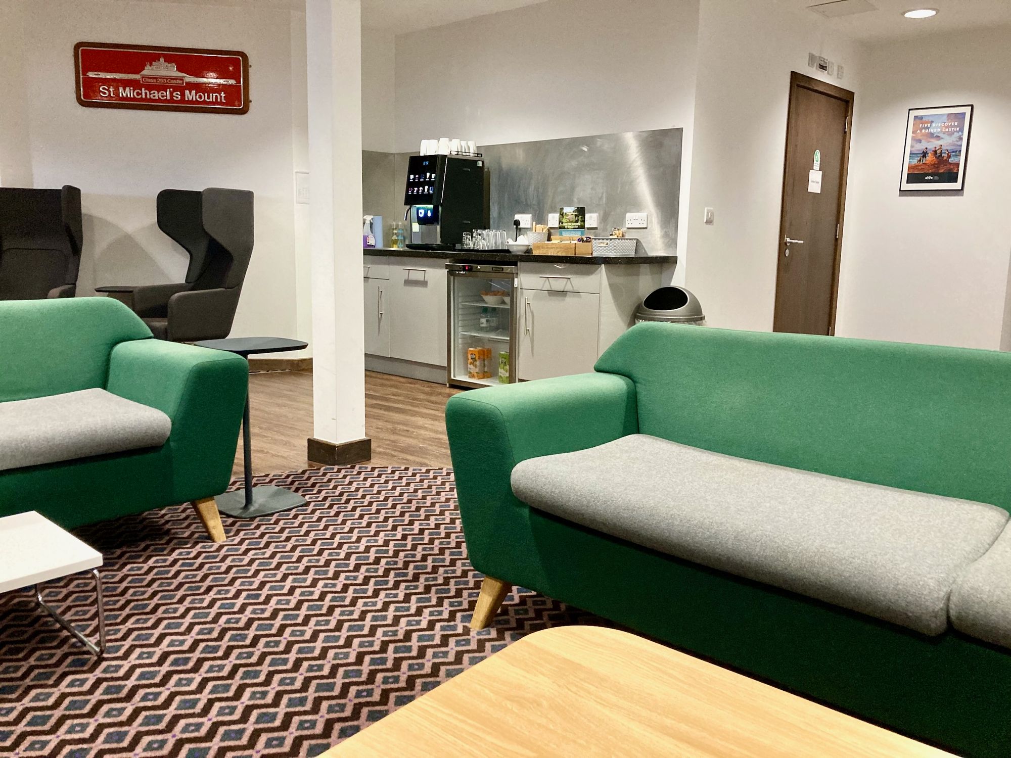 Grüne Sofas in der Lounge, im Hintergrund Kaffeemaschine