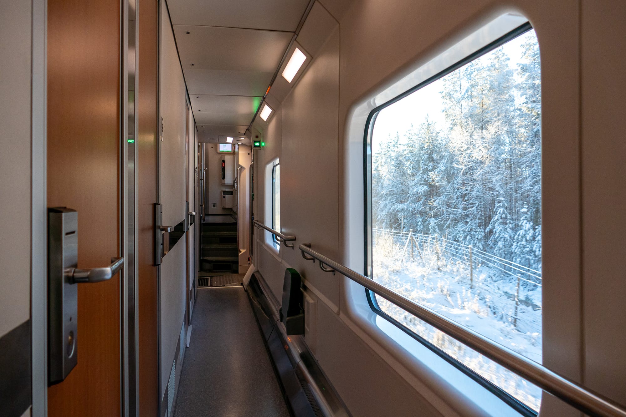 Gang vom Schlafwagen mit Türen, vor dem Fenster eine Winterlandschaft
