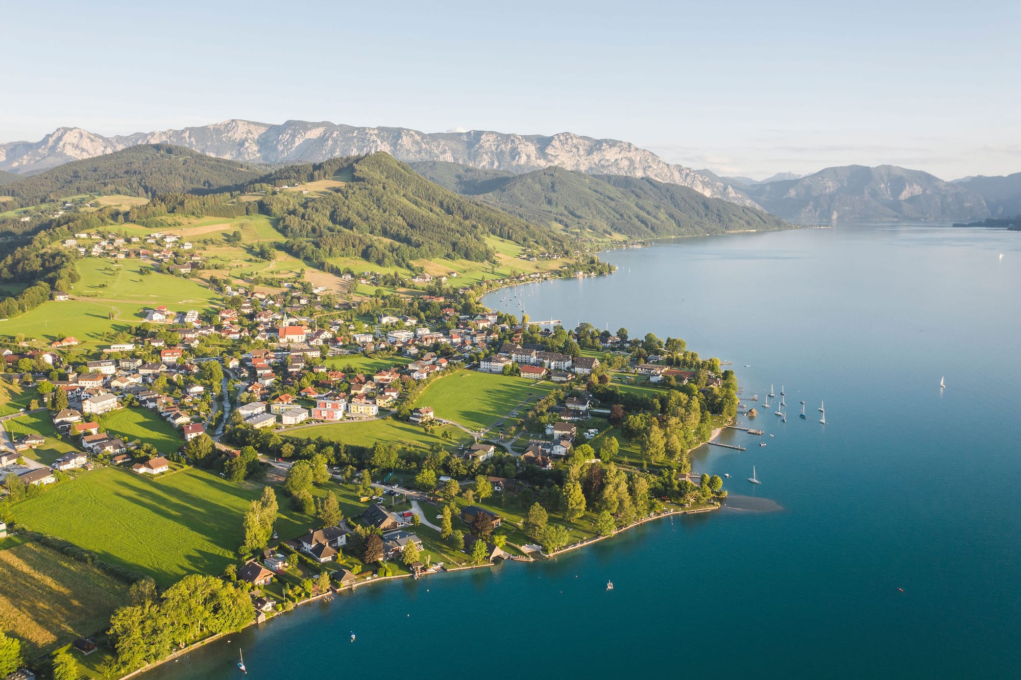 Luftaufnahme von einem Dorf im Salzkammergut mit See und Bergen