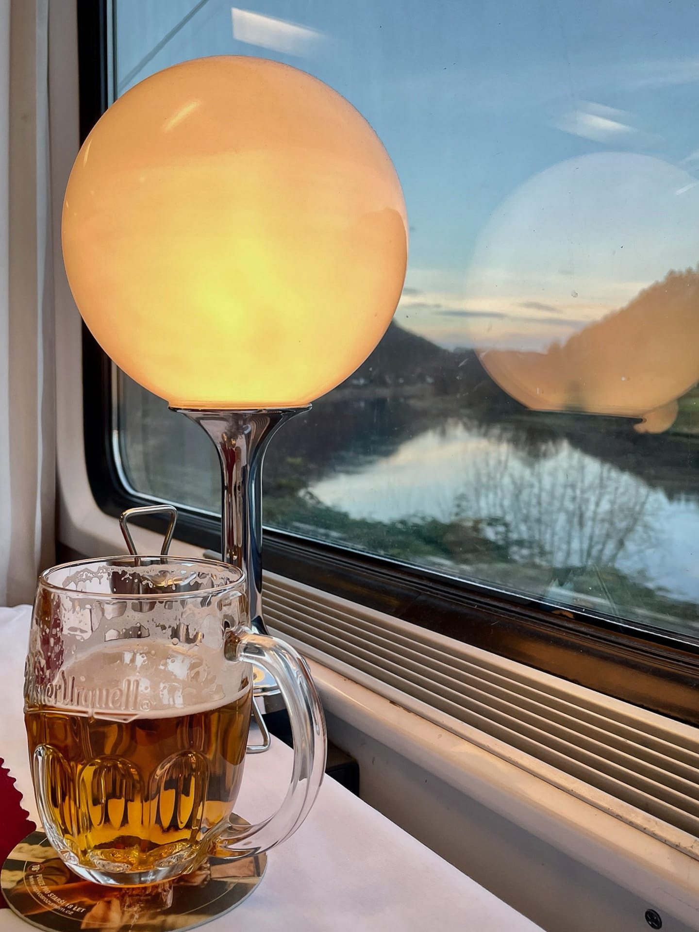 Bierglas und Lampe im tschechischen Speisewagen, vor dem Fenster die Elbe