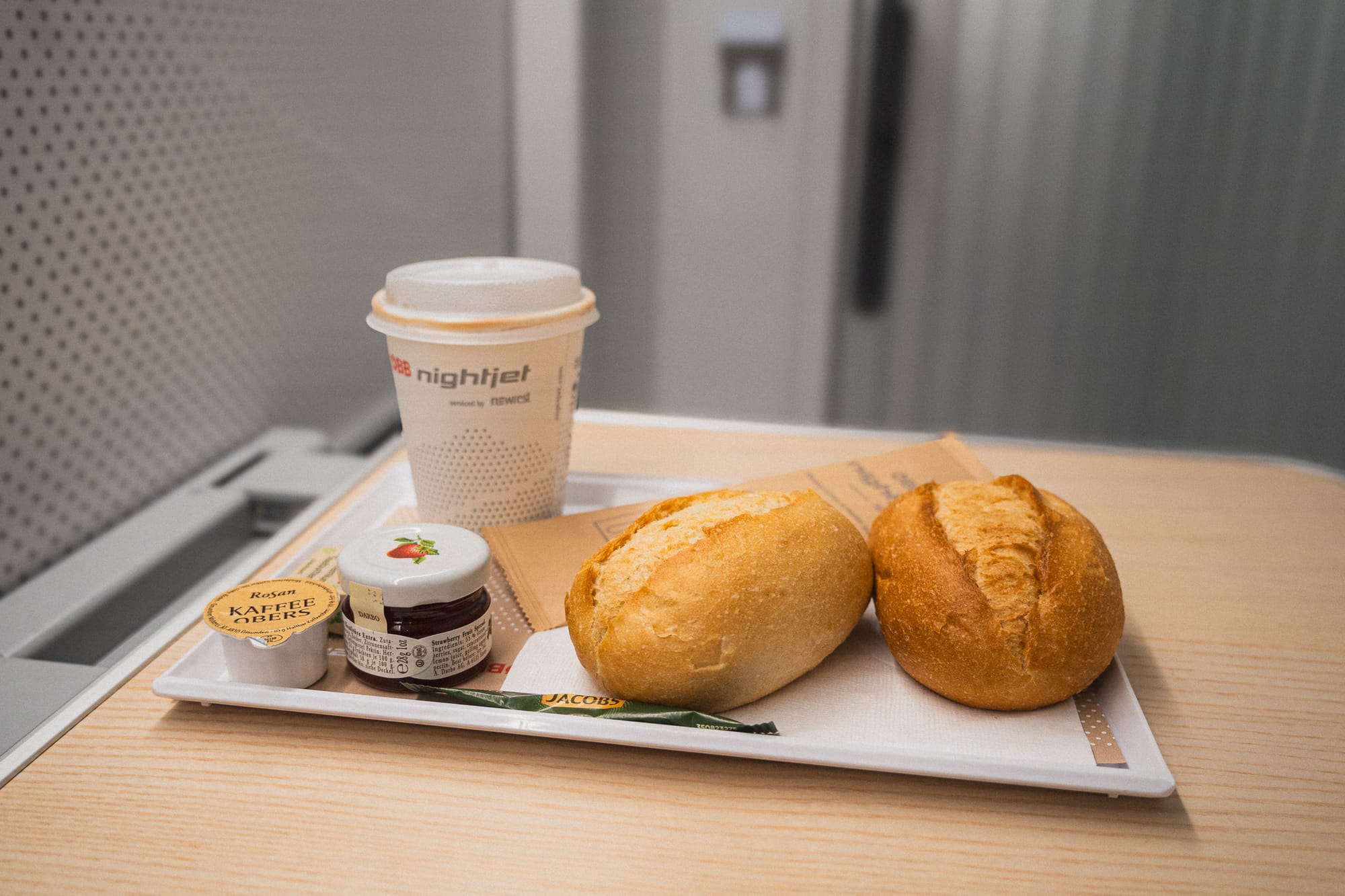 Tablett mit Kaffee, zwei Brötchen und Marmelade