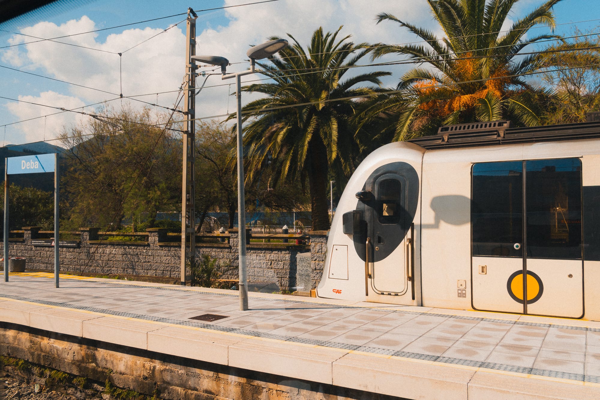 Zug von Euskotren am Bahnhof Deba mit Palmen am Bahnsteig