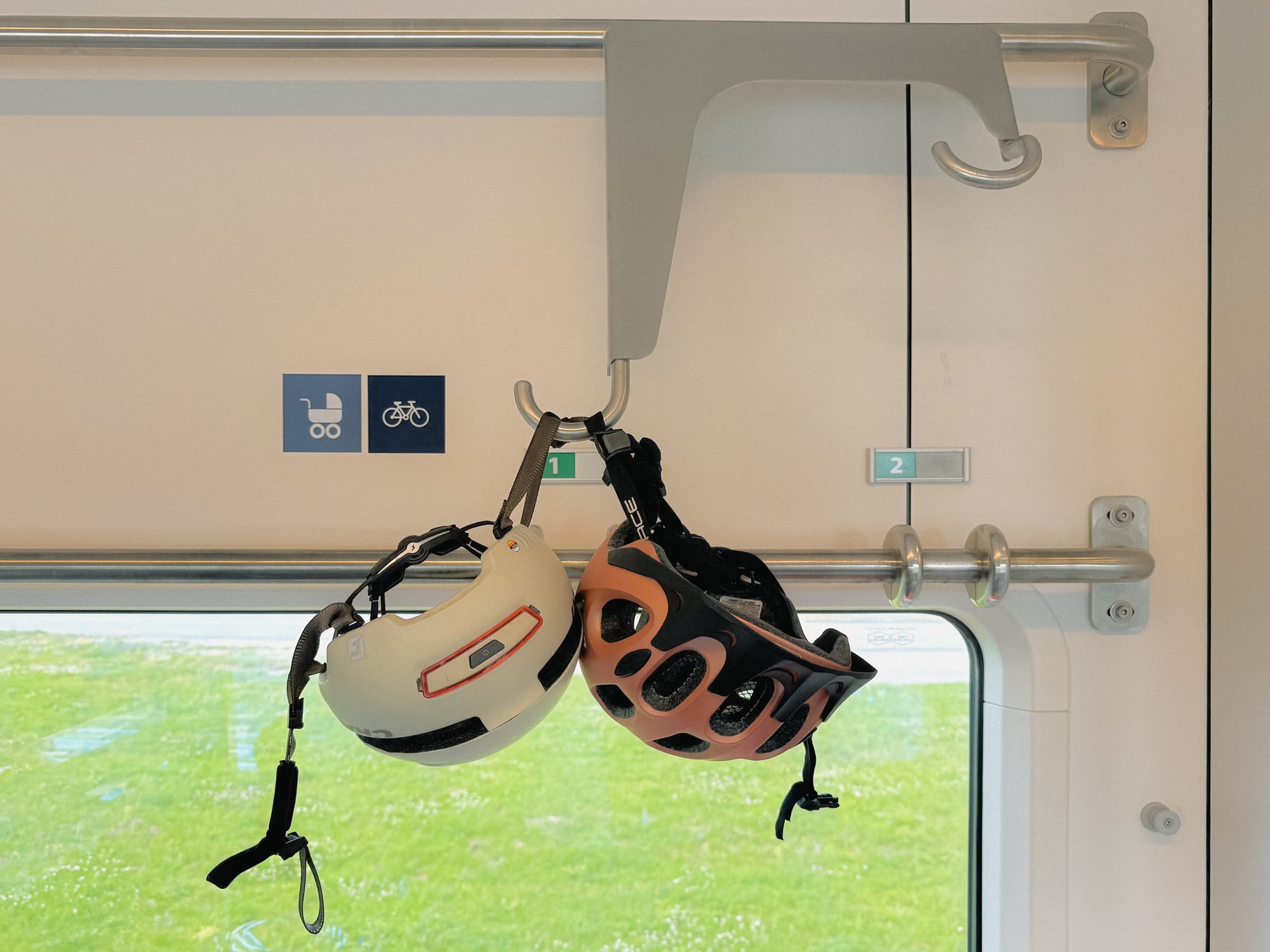 Zwei Fahrradhelme hängen im Zug