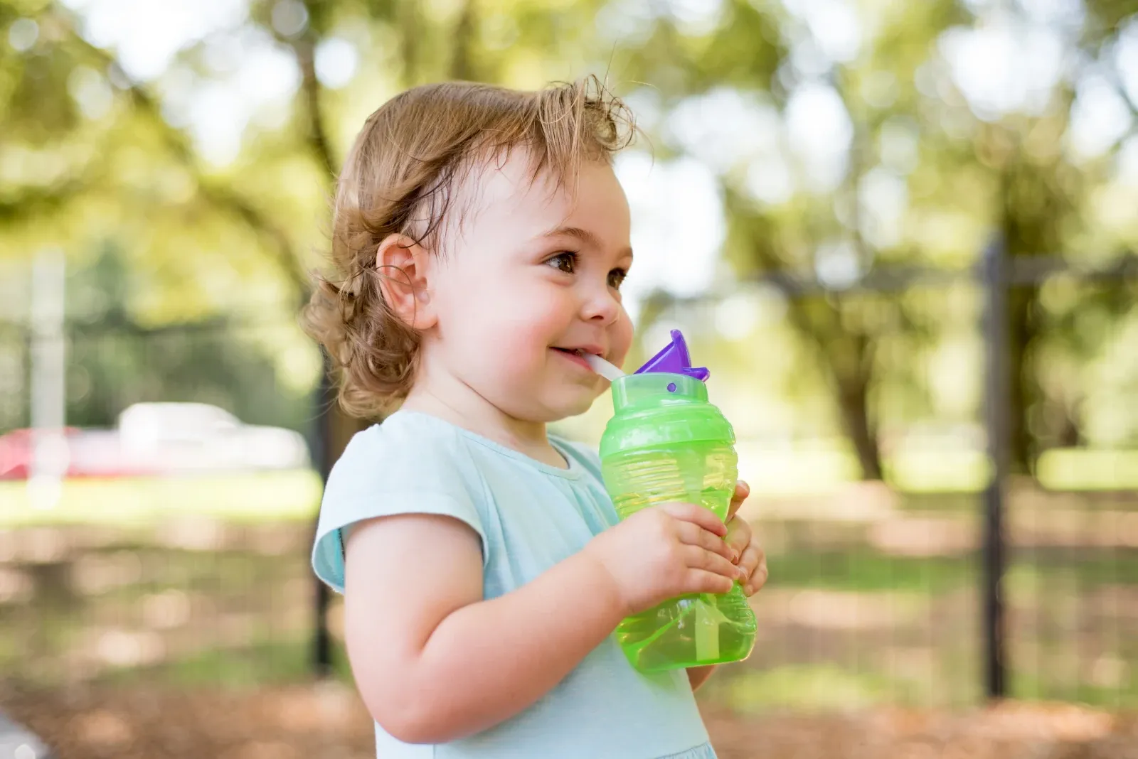 Young child drinking water outdoors during hot weather