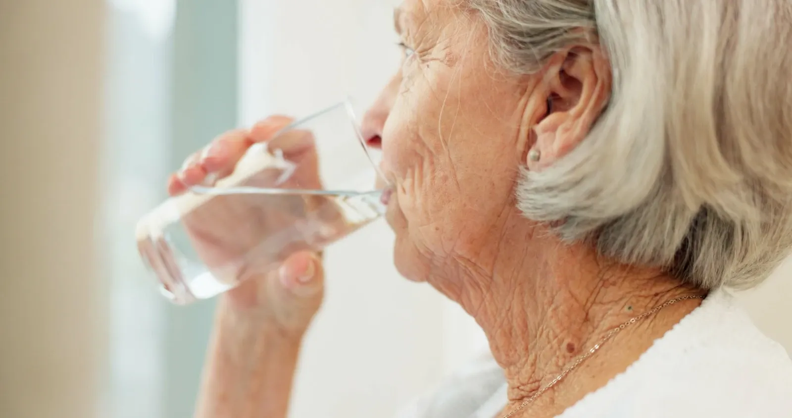 Older woman drinking water to stay hydrated during hot weather