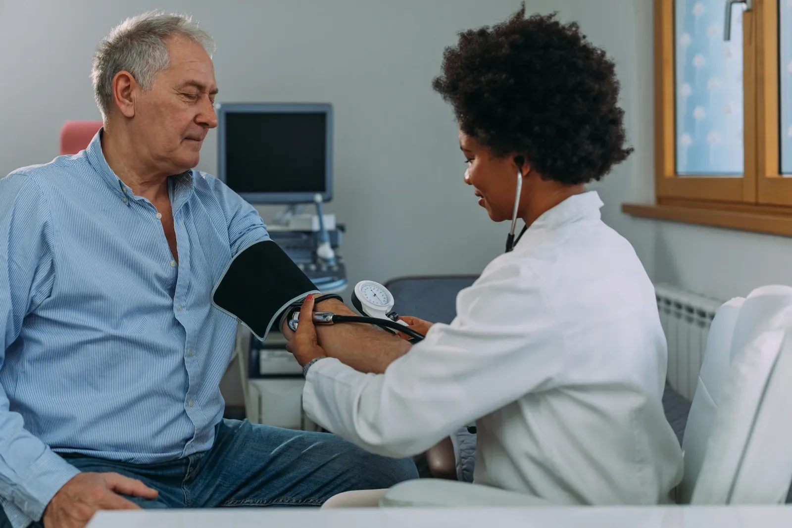 Healthcare professional checking a man's blood pressure during a routine health assessment.