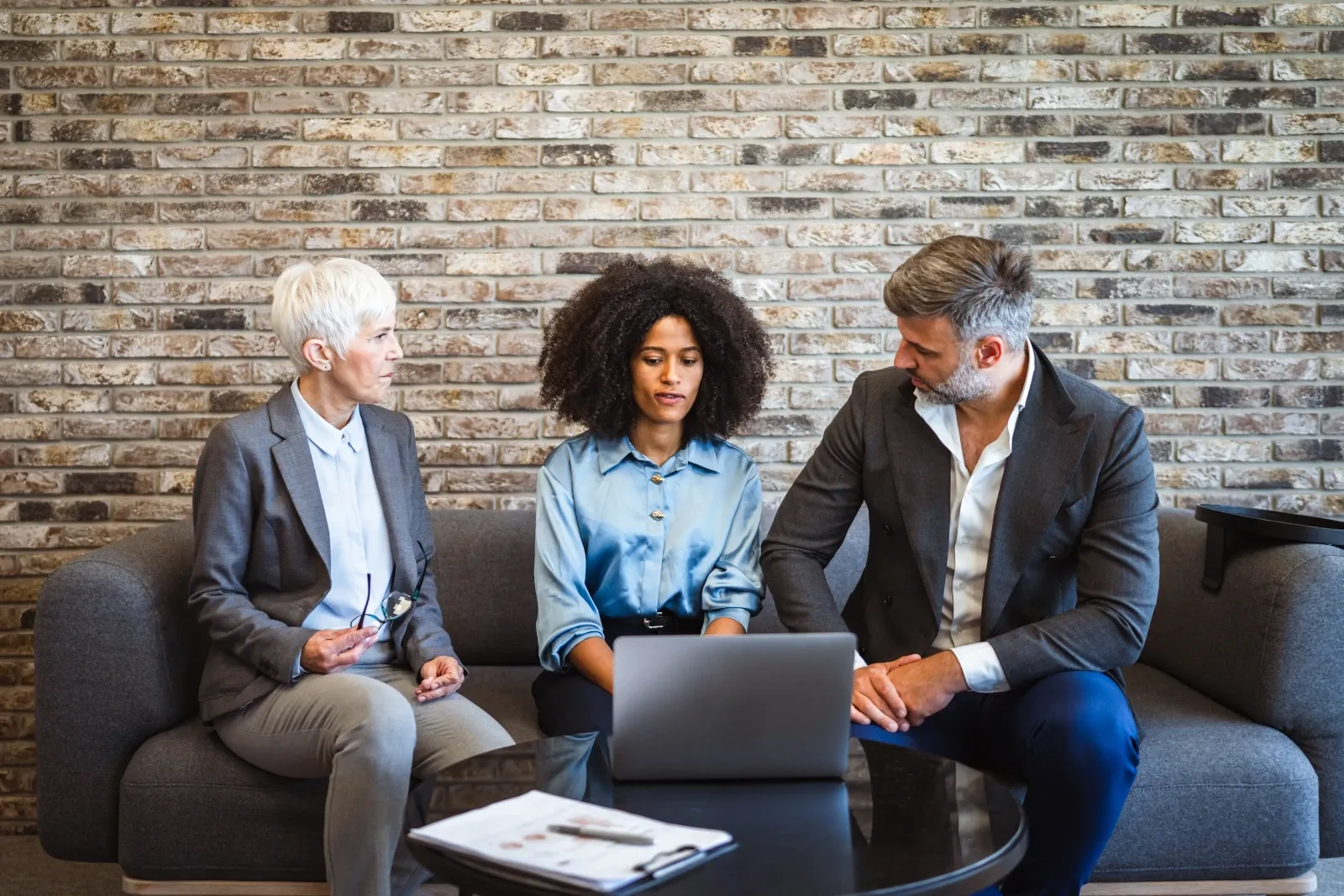 Three colleagues sitting together in conversation, illustrating the importance of supportive workplace relationships and connection.
