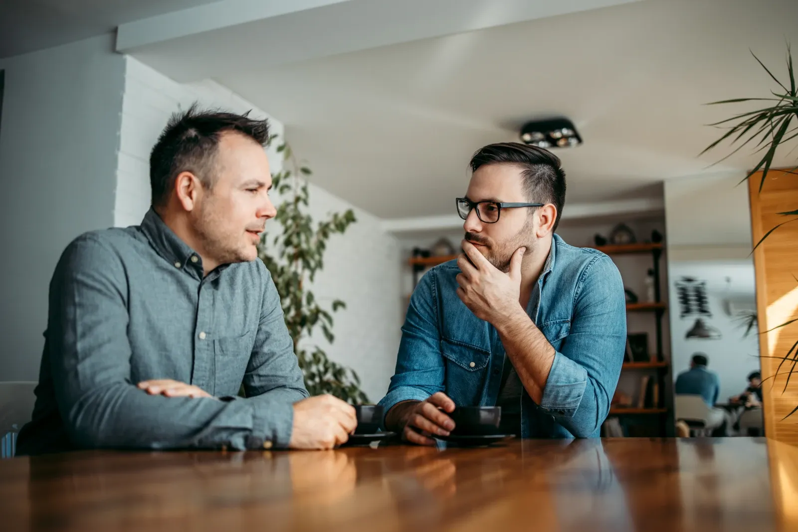 Two colleagues having a private workplace conversation in a quiet meeting area.