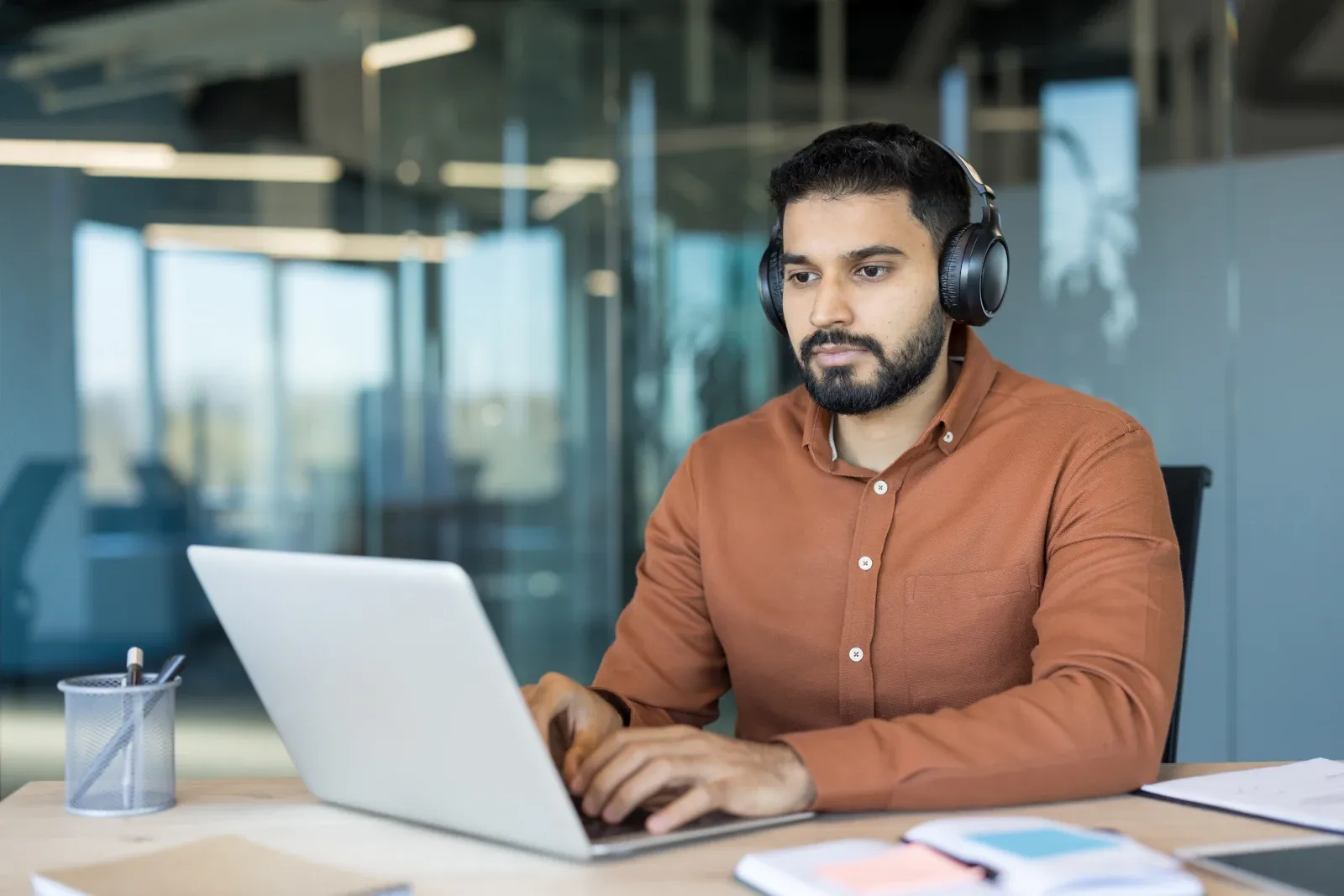 Employee wearing headphones while working on a laptop in an open-plan office.