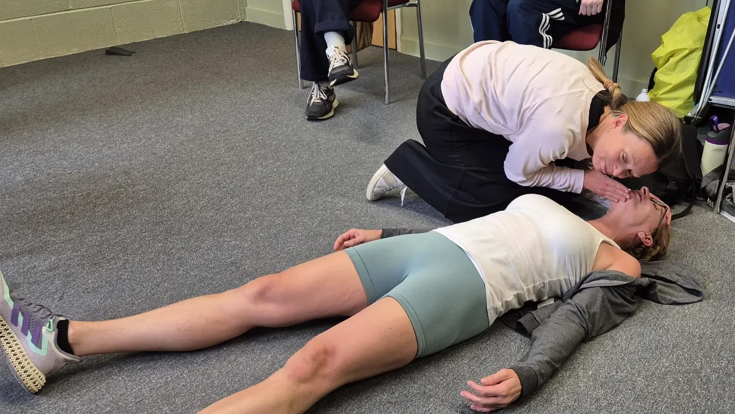Learner practising a breathing check during a workplace first aid course