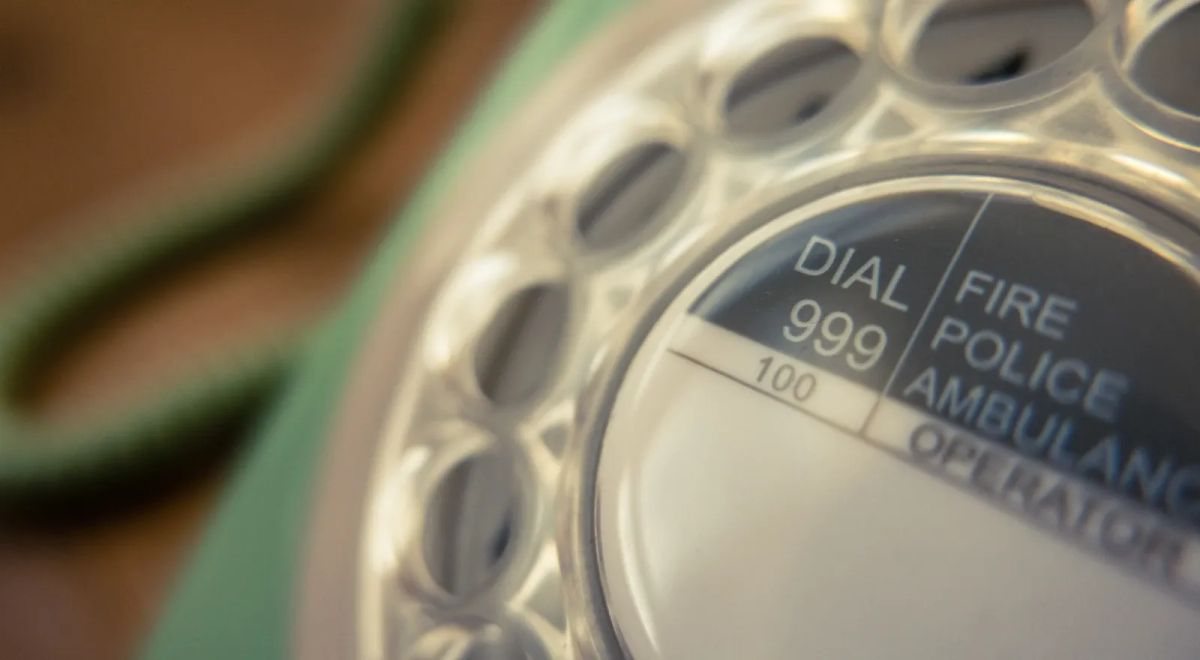 Close-up of an old telephone dial showing 999 for emergency calls.