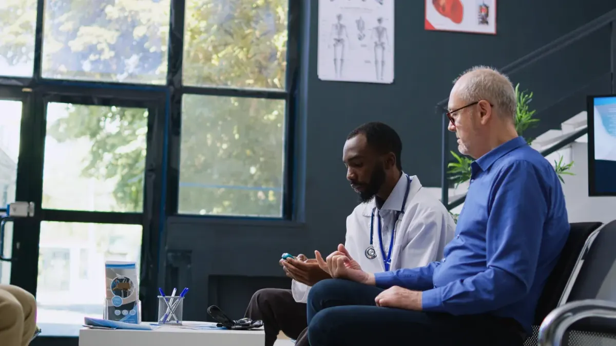 A man discussing his health with a clinician during a routine medical appointment.