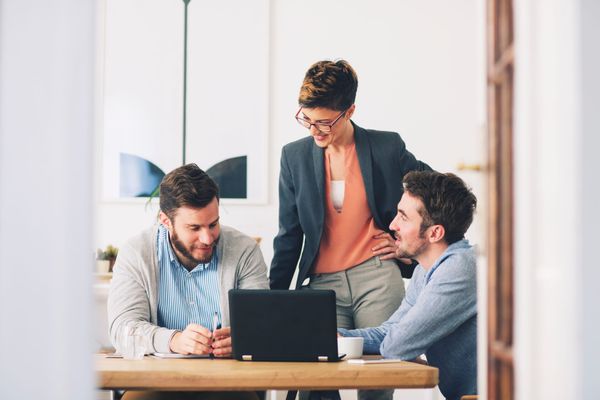 Colleagues in a workplace having a calm, supportive conversation around a desk.