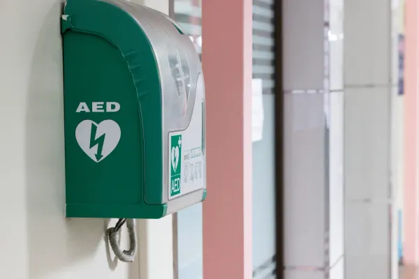 Wall-mounted AED in a workplace corridor, positioned for quick access in an emergency