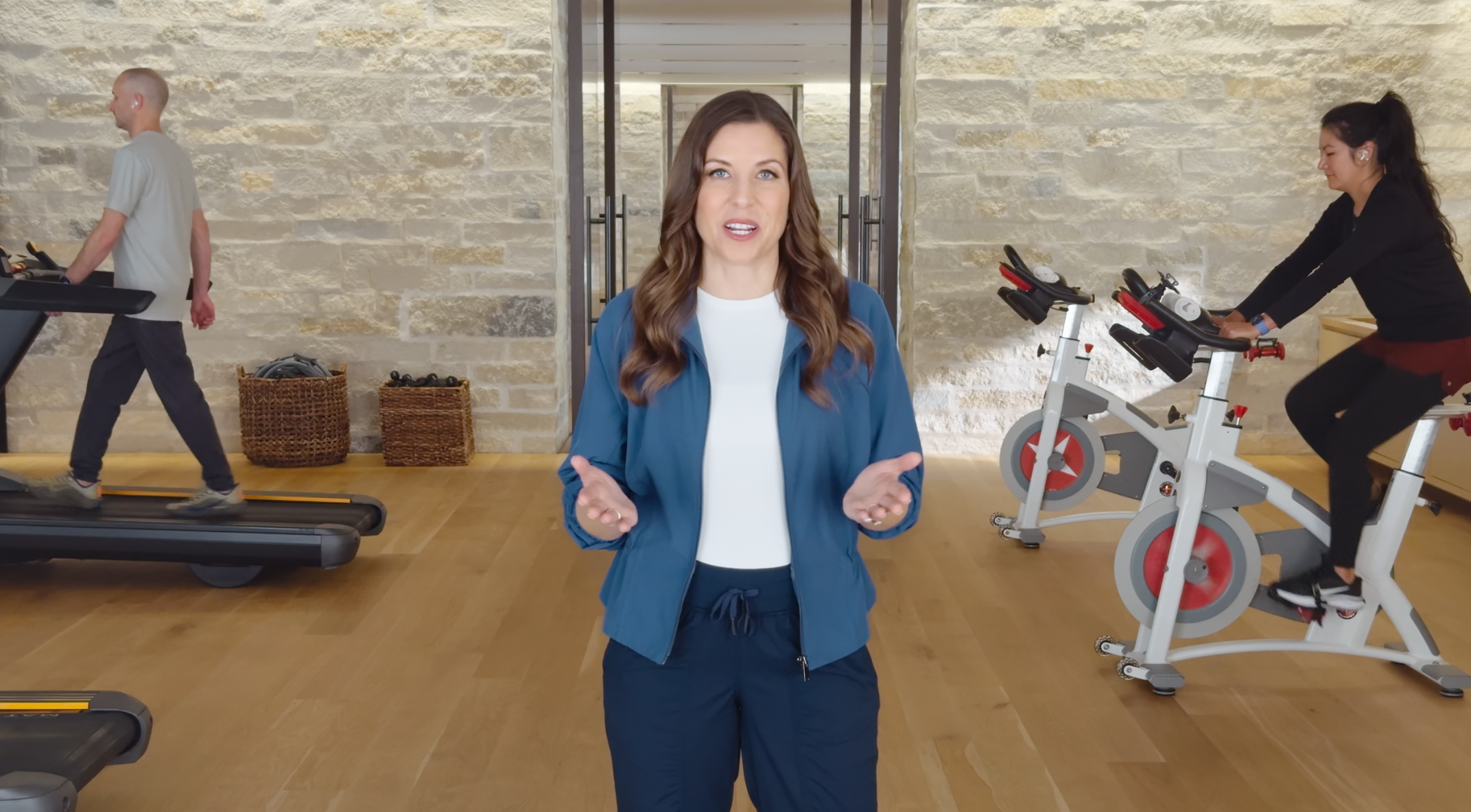 Screenshot from Apple Keynote showing someone talking with 2 people working out in the background.