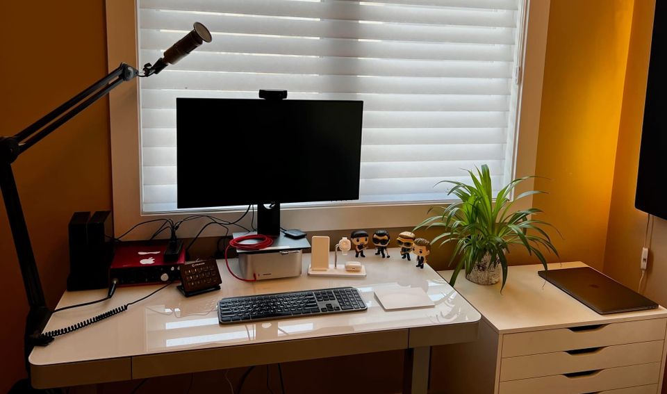 A view of my desk when it was clean with a Mac Studio, monitor, keyboard, mic on a boom stand, and a plant.