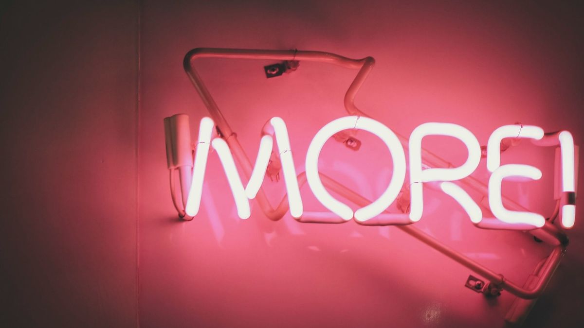 the word more in bright pink neon tube lighting against a darker pink wall