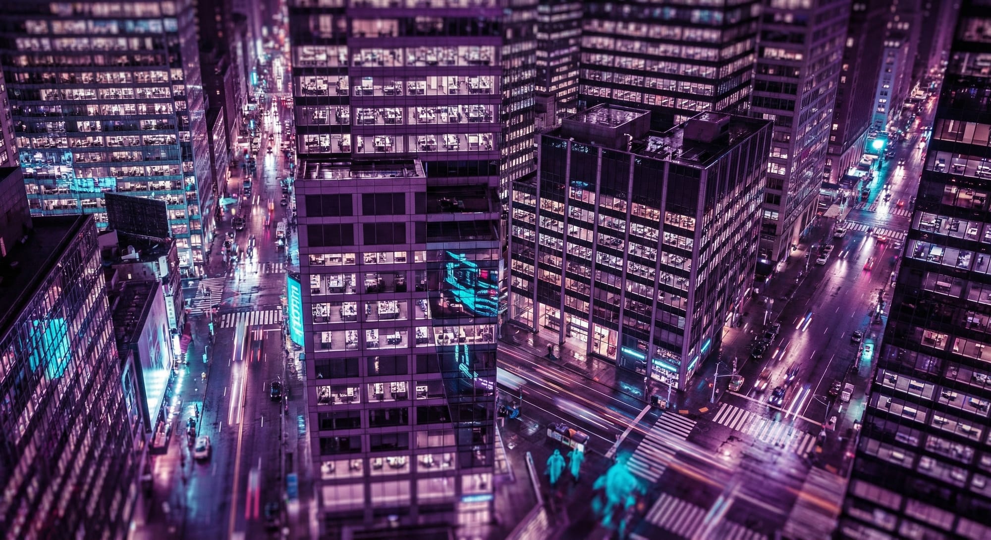 Luchtfoto van verlichte kantoorgebouwen en straten in een moderne stad bij nacht met paarse en blauwe tinten.