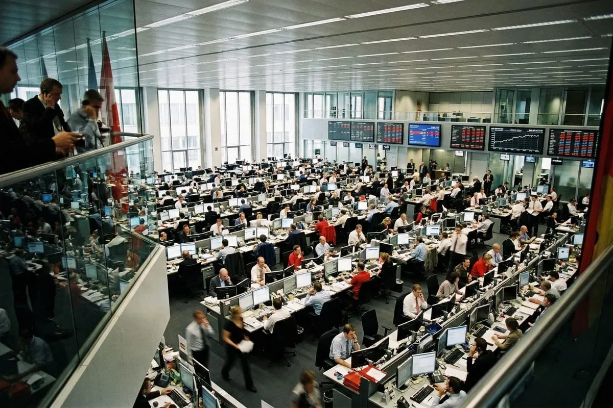 Drukke handelsvloer met tientallen medewerkers aan computerdesks, grote schermen met beursdata, glazen wanden en moderne kantoorinrichting