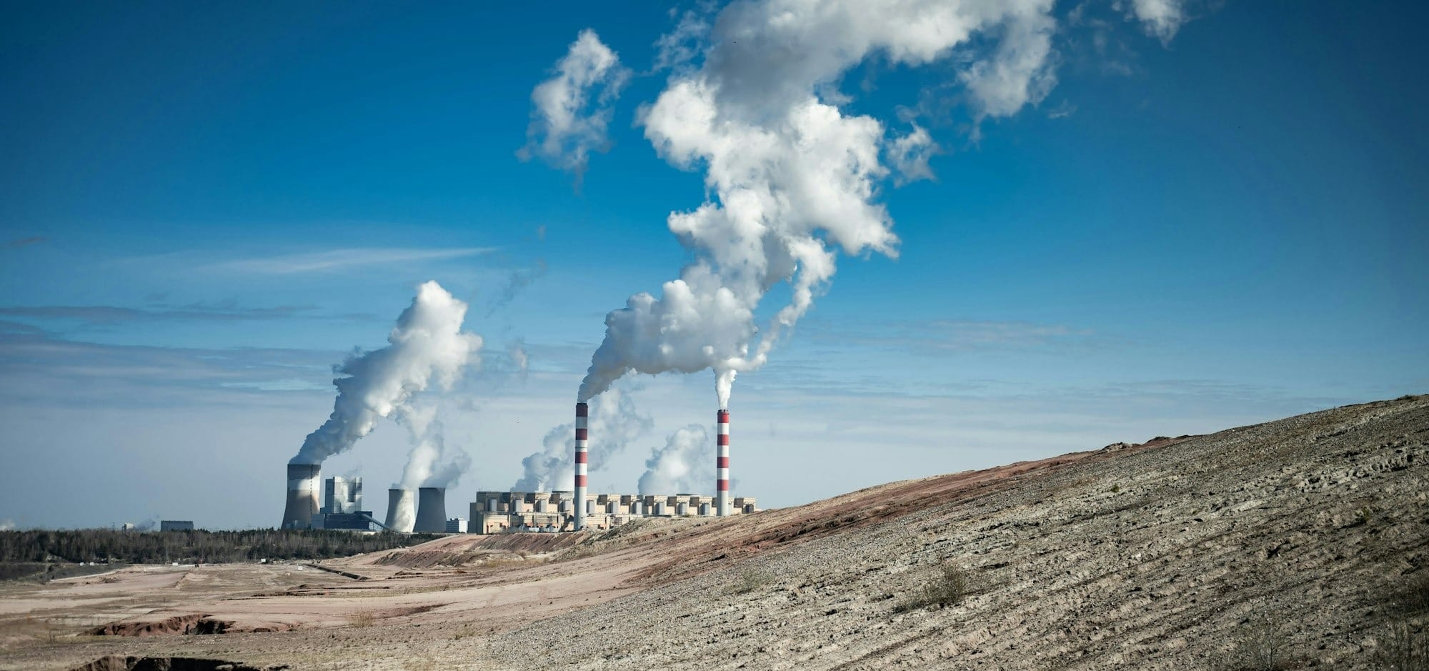 Industrial power plant emitting smoke under a clear blue sky