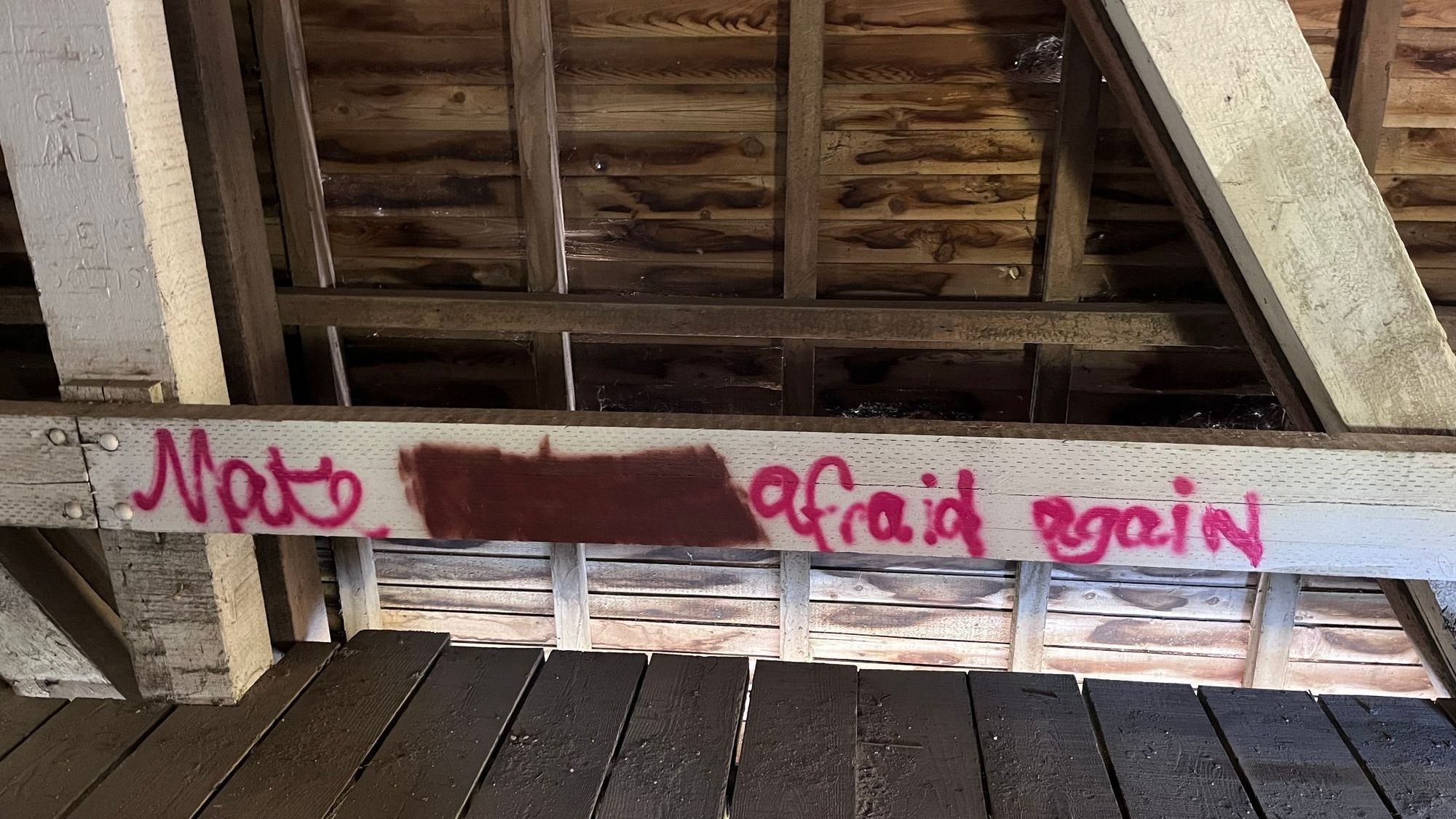 Bridge graffiti that says 'Make blank afraid again' with second word blacked out