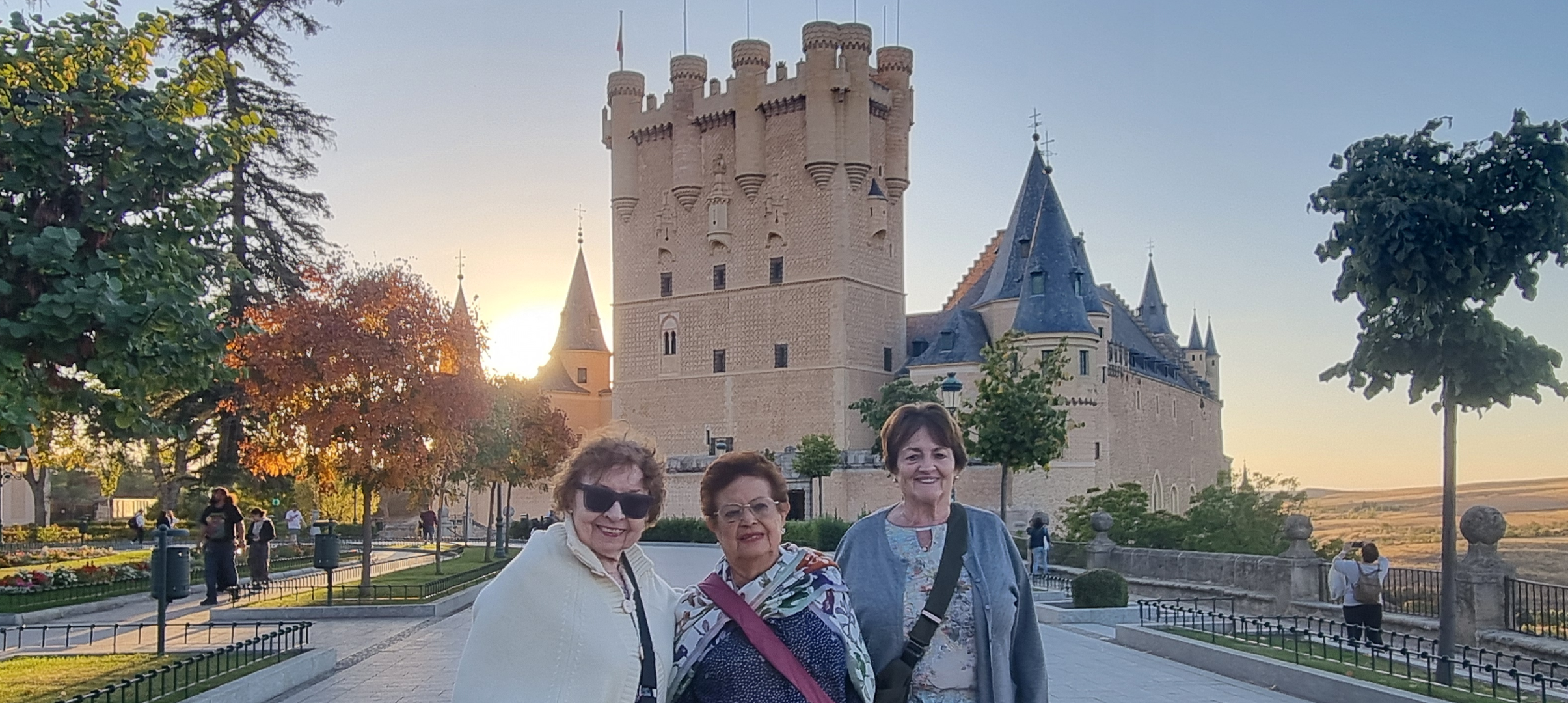 tres adultas mayores frente a un castillo en un viaje por Europa
