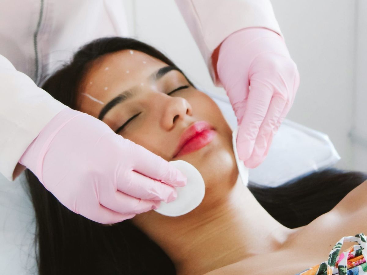 Woman receiving Botox injections on the forehead with marked points, looking relaxed and comfortable as the doctor prepares her face for treatment.