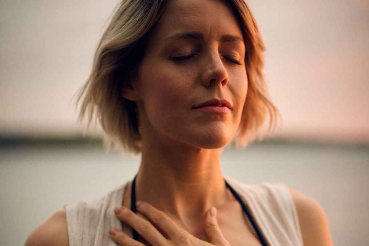 Woman holding her chest, displaying a moment of vulnerability and courage as she overcomes anxiety and takes a step towards confidence.