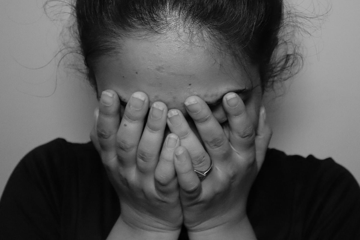Woman gently covering her face with her hands, representing the complex emotions and hidden feelings associated with aging and self-image.