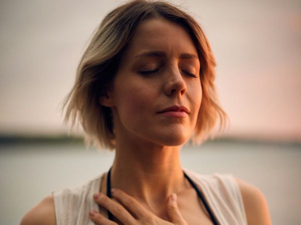Woman holding her chest, displaying a moment of vulnerability and courage as she overcomes anxiety and takes a step towards confidence.