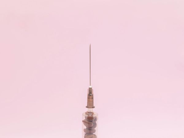 Close-up of a syringe and needle, illustrating the tools involved in non-surgical facial rejuvenation treatments.