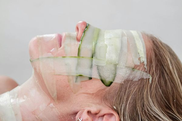 Woman with cucumber strips on her face, symbolizing natural and soothing skincare treatments to refresh and rejuvenate healthy skin.