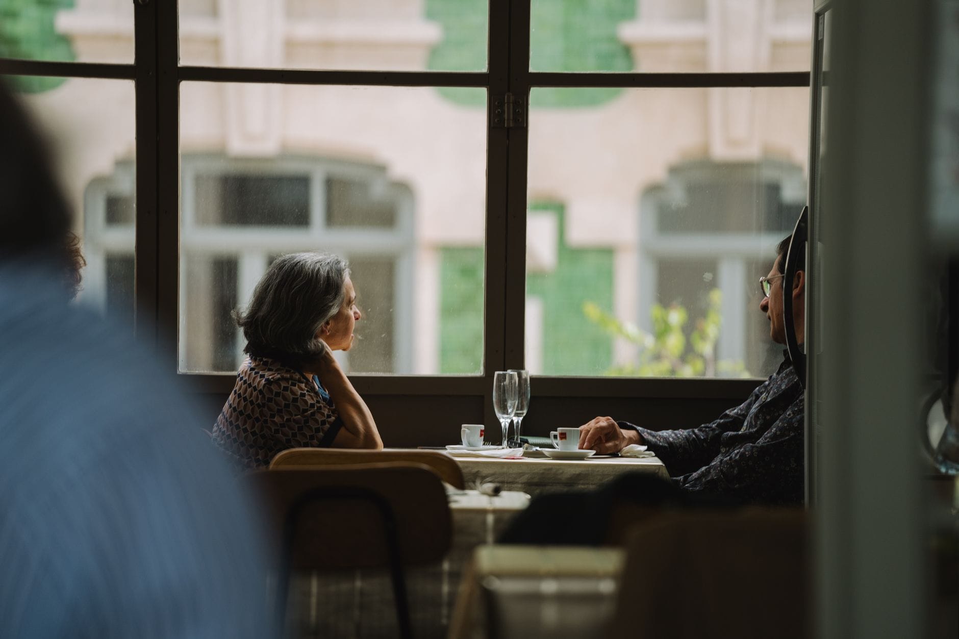 Elderly couple sitting by the window, enjoying coffee at a cozy café.
