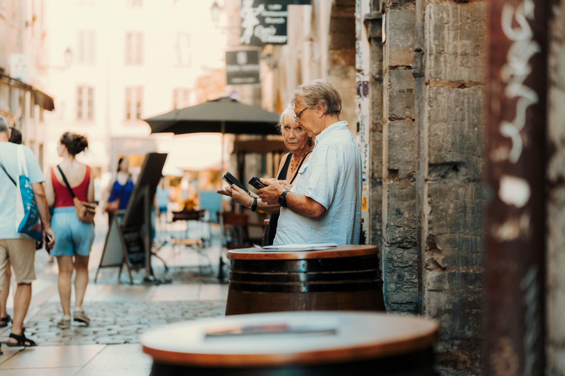 A senior couple examines their surroundings in a quaint European street setting.