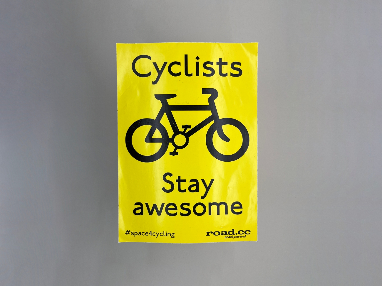 A bright yellow A4 size poster that says Cyclists above an icon of a bicycle. Under it says Stay awesome, #space4cycling road.cc 