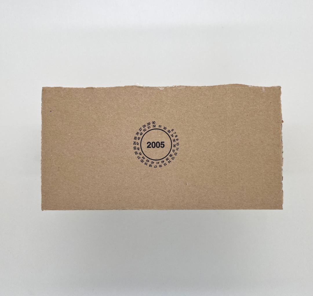 Piece of brown cardboard with a circle containing the date 2005, around which the numbers 6 to 30 and 31 to 52 run around. 