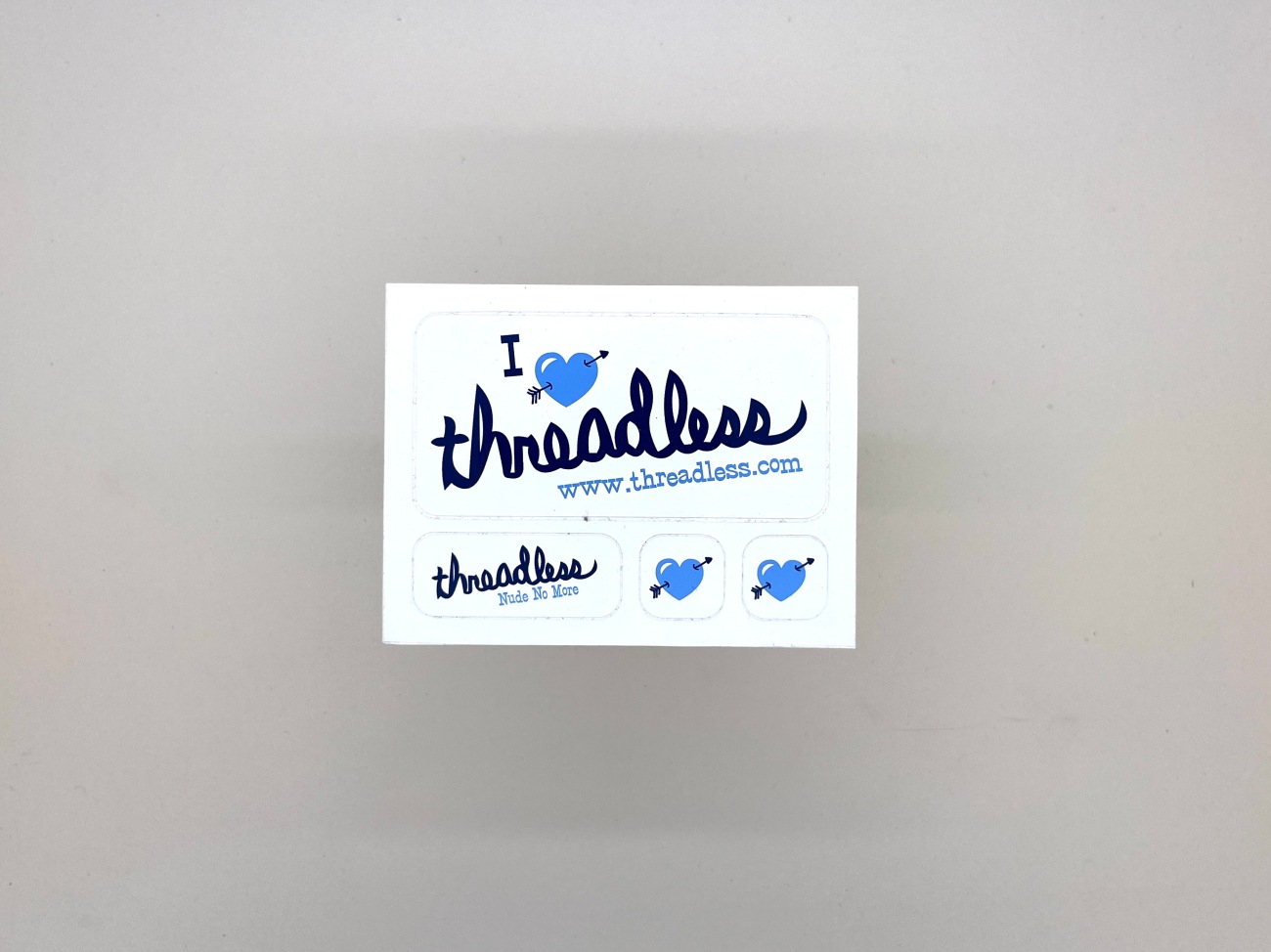 A sticker saying I heart icon (with an arrow through it) threadless. Plus a small one that just says threadless and another two tiny ones of heart icons with arrows though them 