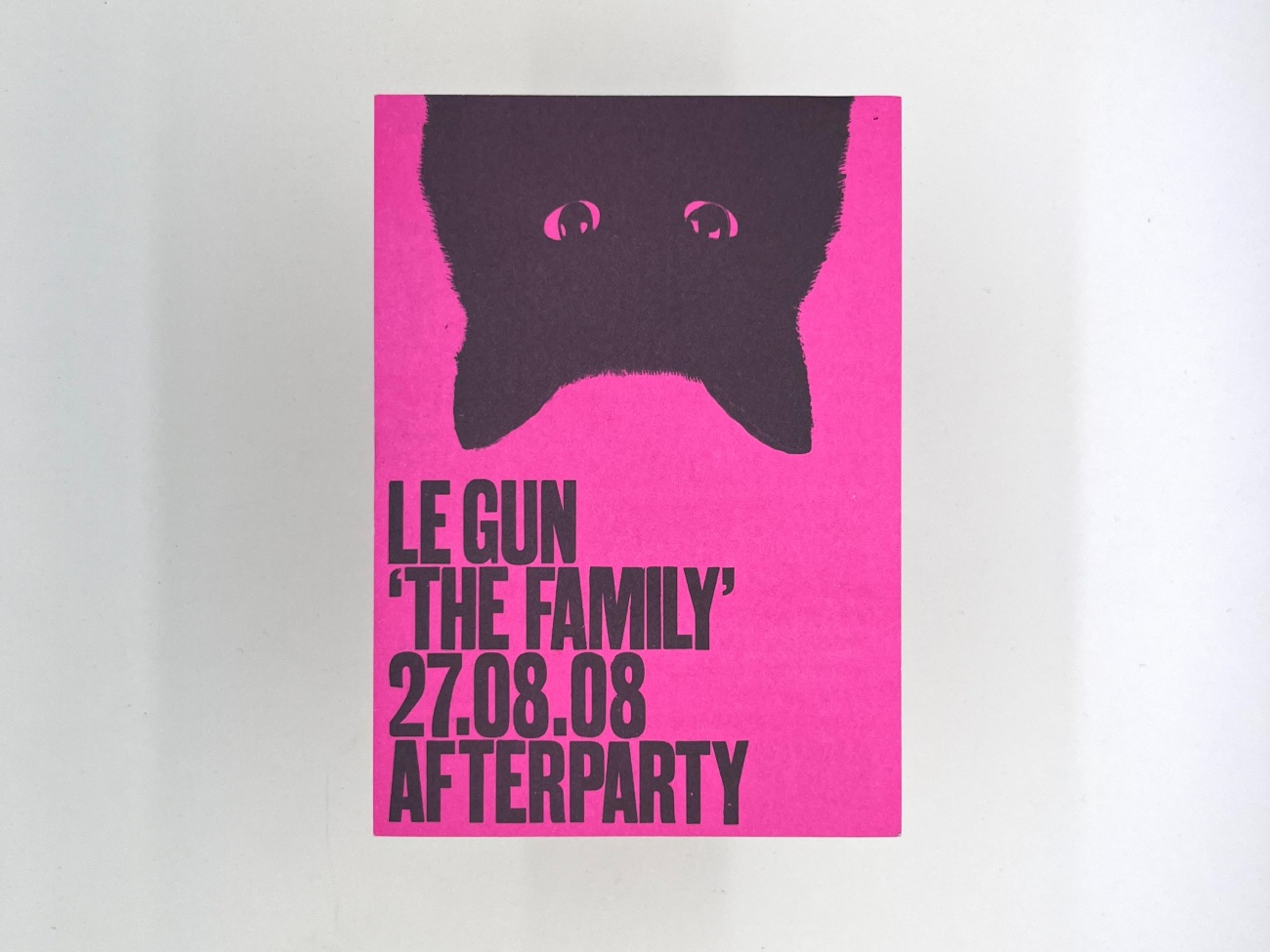 A bright pink almost magenta postcard with blank ink printing. One side with the silhouetted head of a black cat were just its eyes are visible and the all caps text reading Le Gun The Family 27.08.08 Afterparty