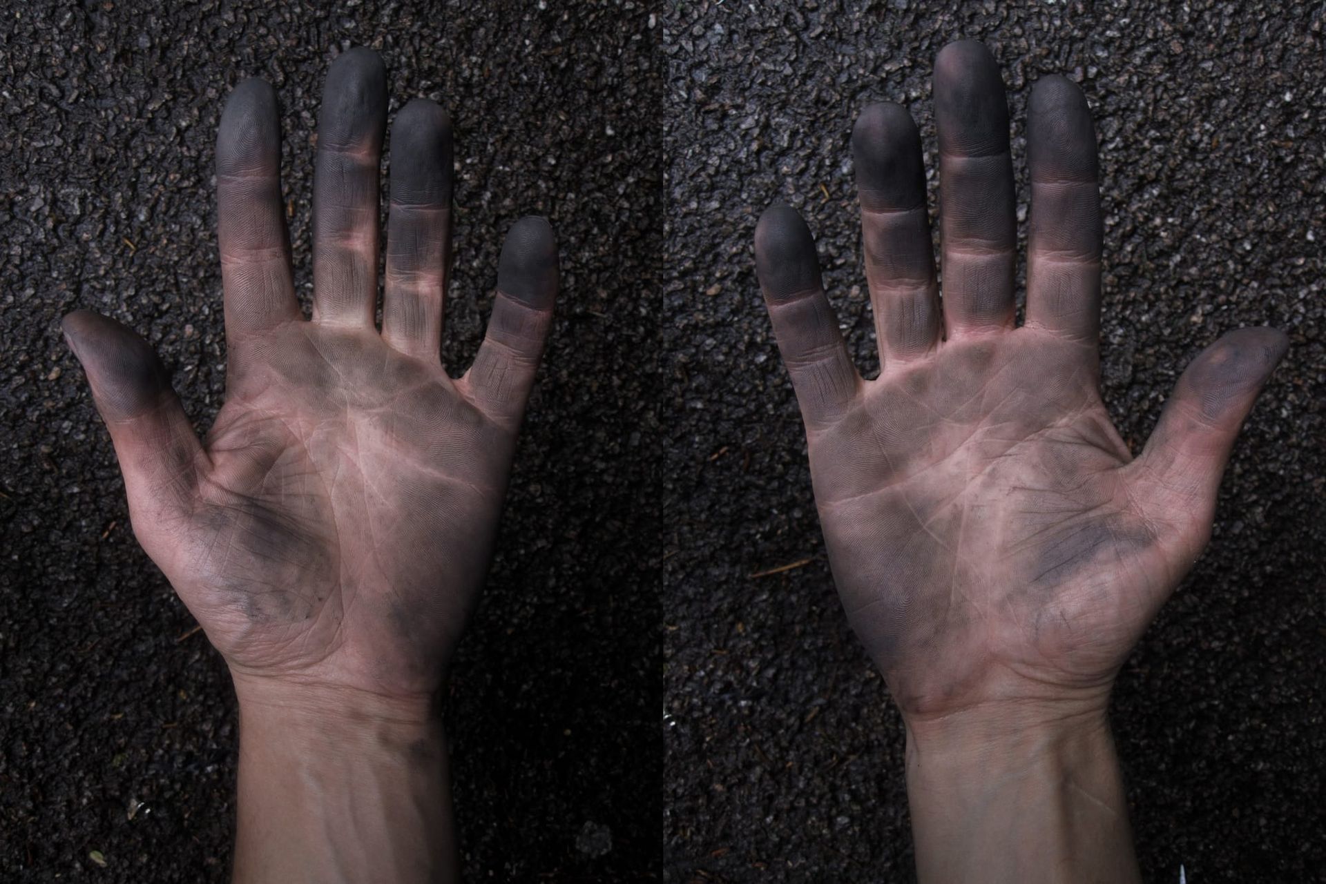 Two caucasian hands held out  against an asphalt background, and covered in chain oil and tyre dirt after fixing a puncture. 