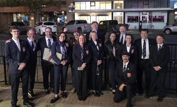 Several people in blue suits, ties, and WTSDA patches, standing outside at night