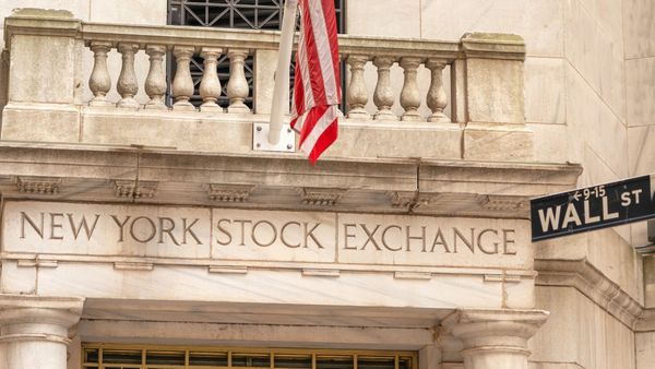 New York Stock Exchange facade and Wall Street sign beneath the American flag.