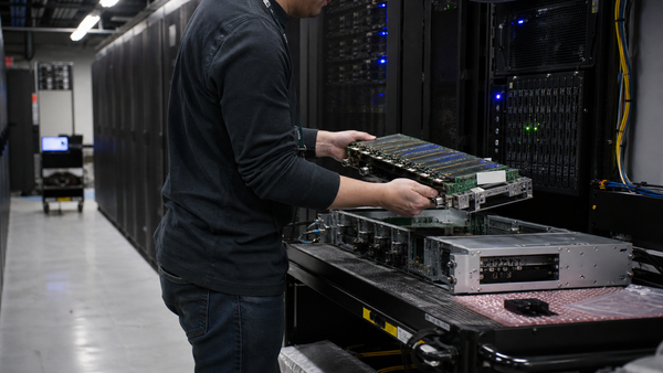 A data-center technician installs an AI accelerator and memory assembly into a server chassis.
