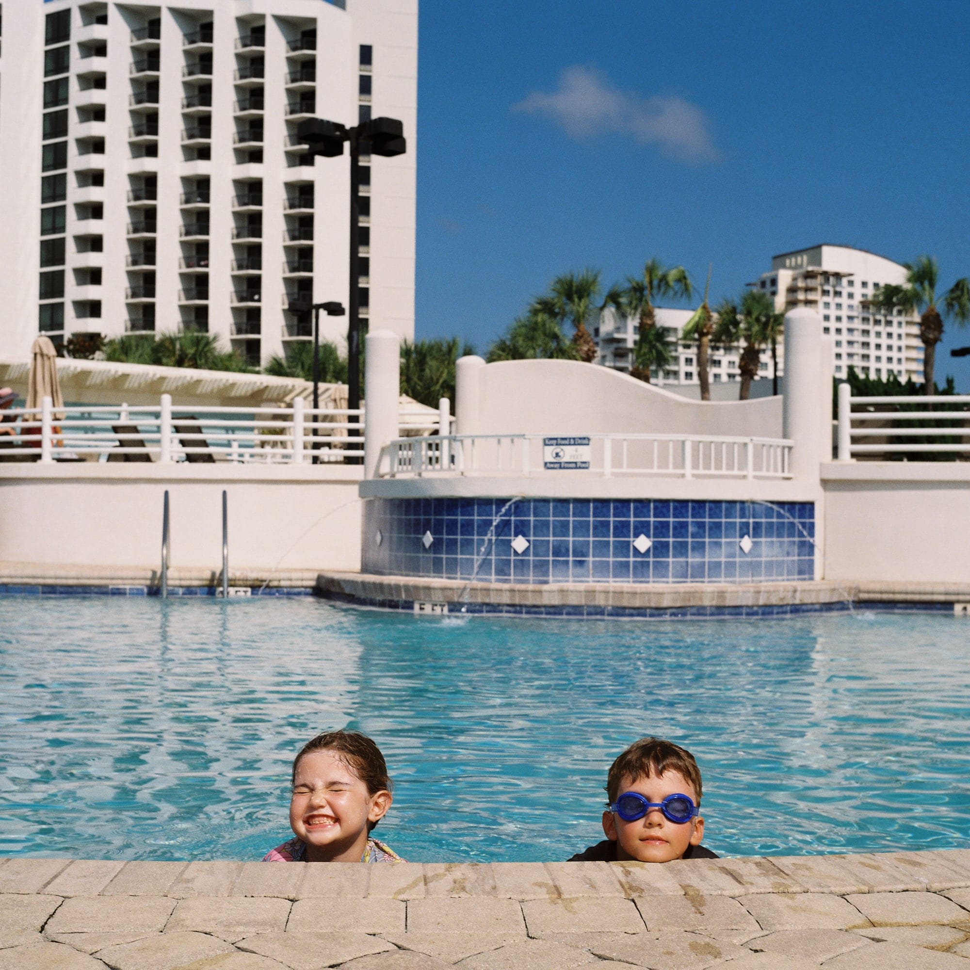 My kids on the edge of the pool with just their heads poking out of the water and resting on the edge.