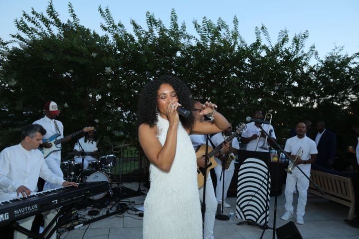 A vocalist in a white dress performs outdoors with Newark Symphony Hall’s 1st Stage Orchestra at The Symphony at Sunset.