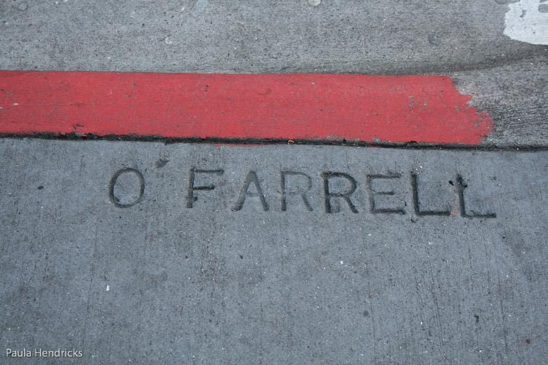 The street name “O’FARRELL, written in the sidewalk.” />
<figcaption style=